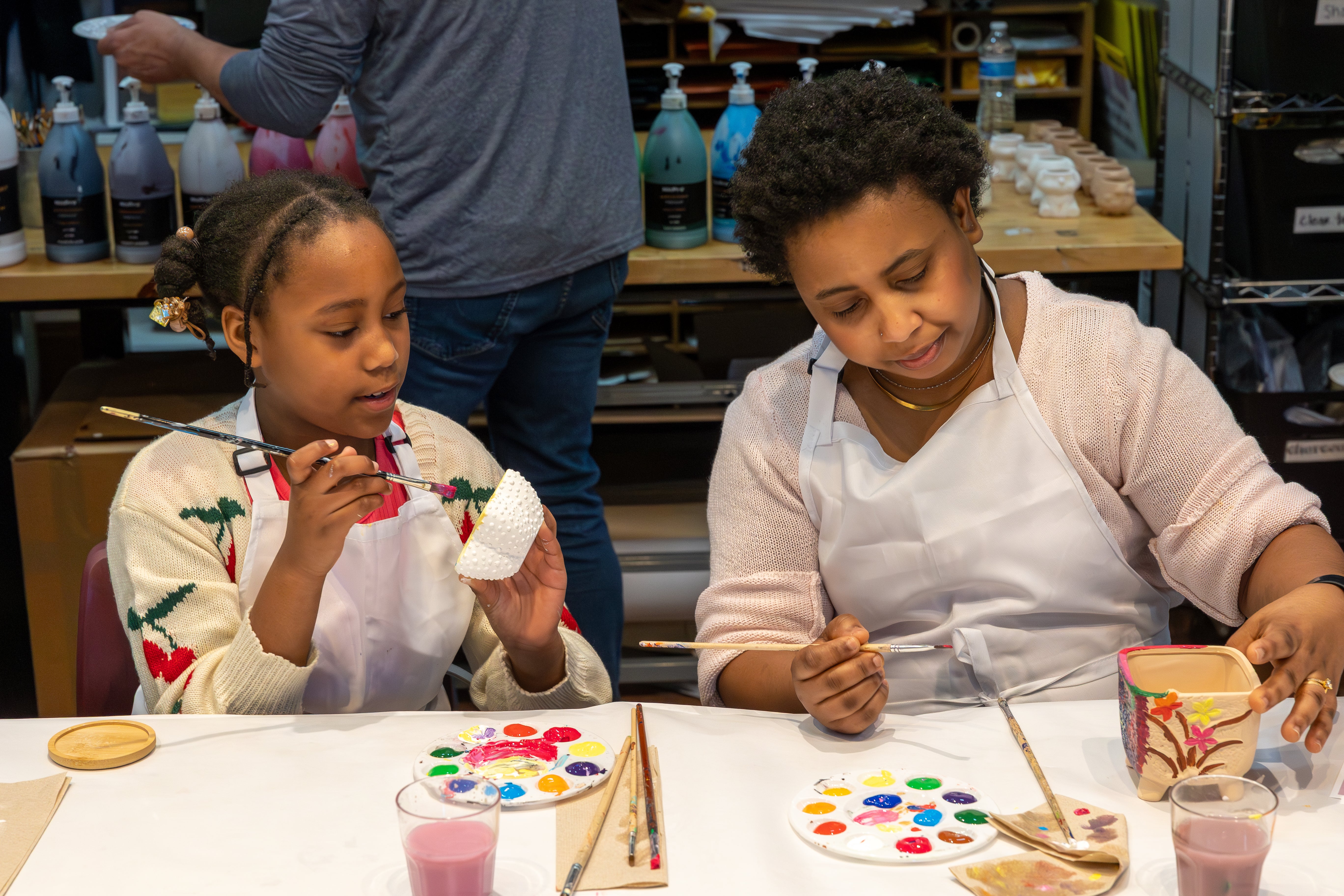 A mother and dughter painting pottery.