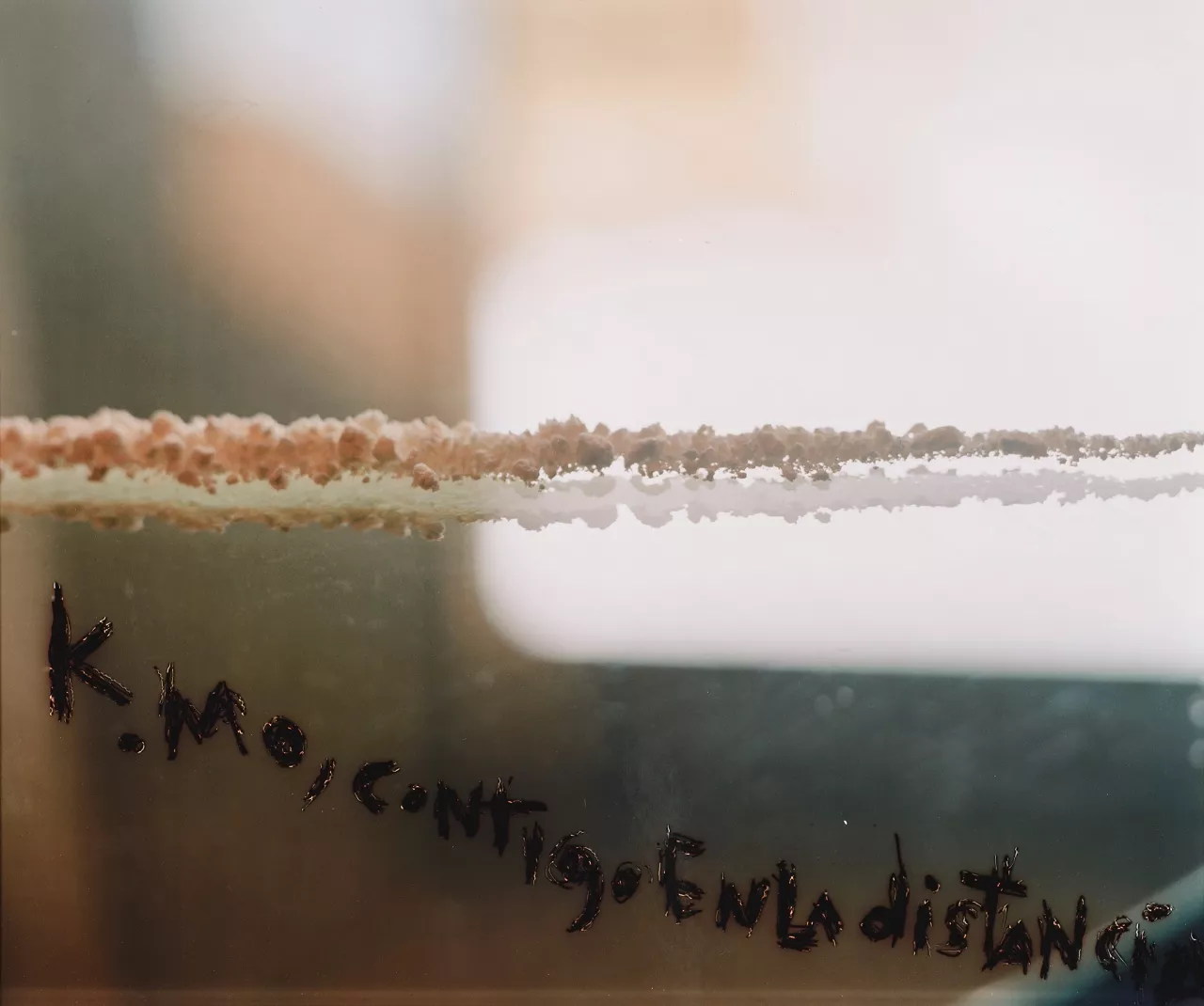 Abstract photo with a cloud like line through the middle of the image and Spanish text handwritten below it.