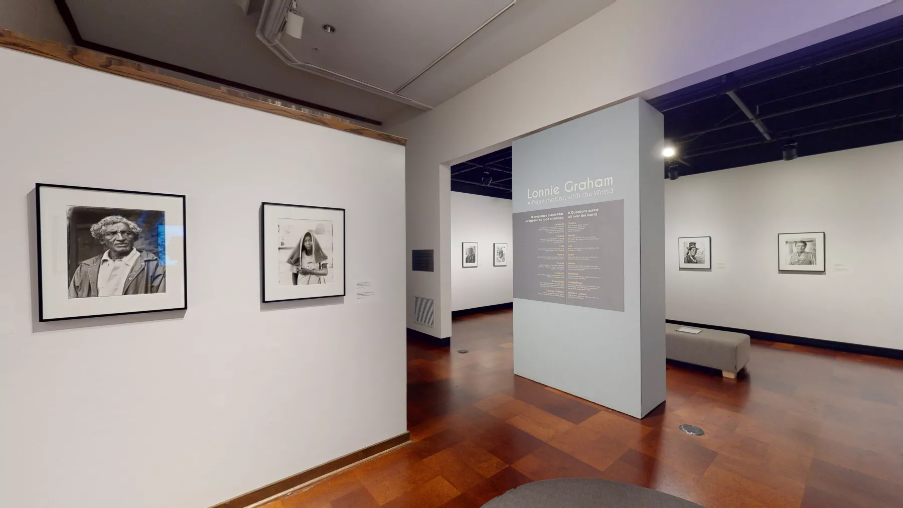 View of a gallery space with framed photographs on the walls. It is a view of two separate rooms.