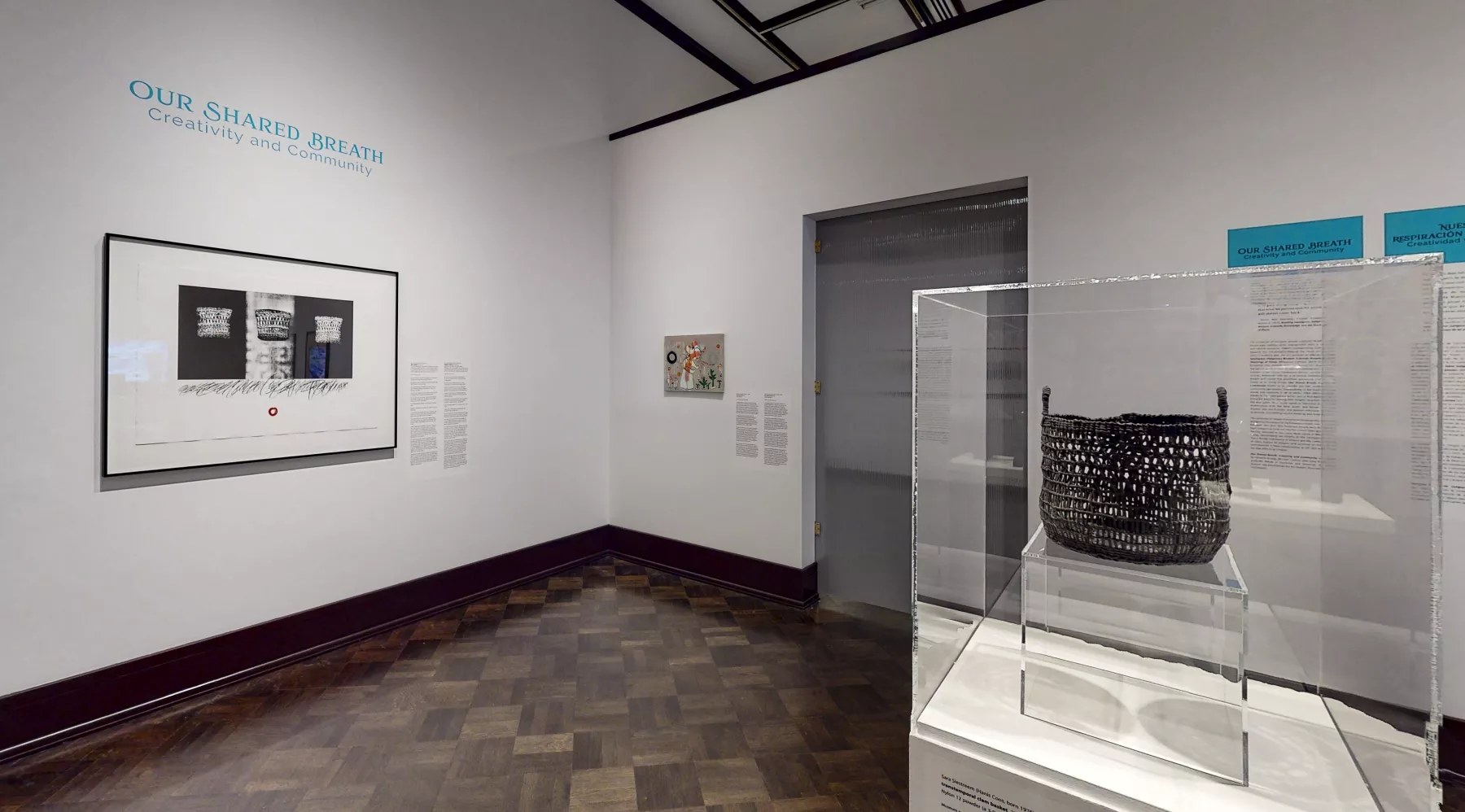Galrry view of a braided basket under glass and framed prints on the wall under the title of the show