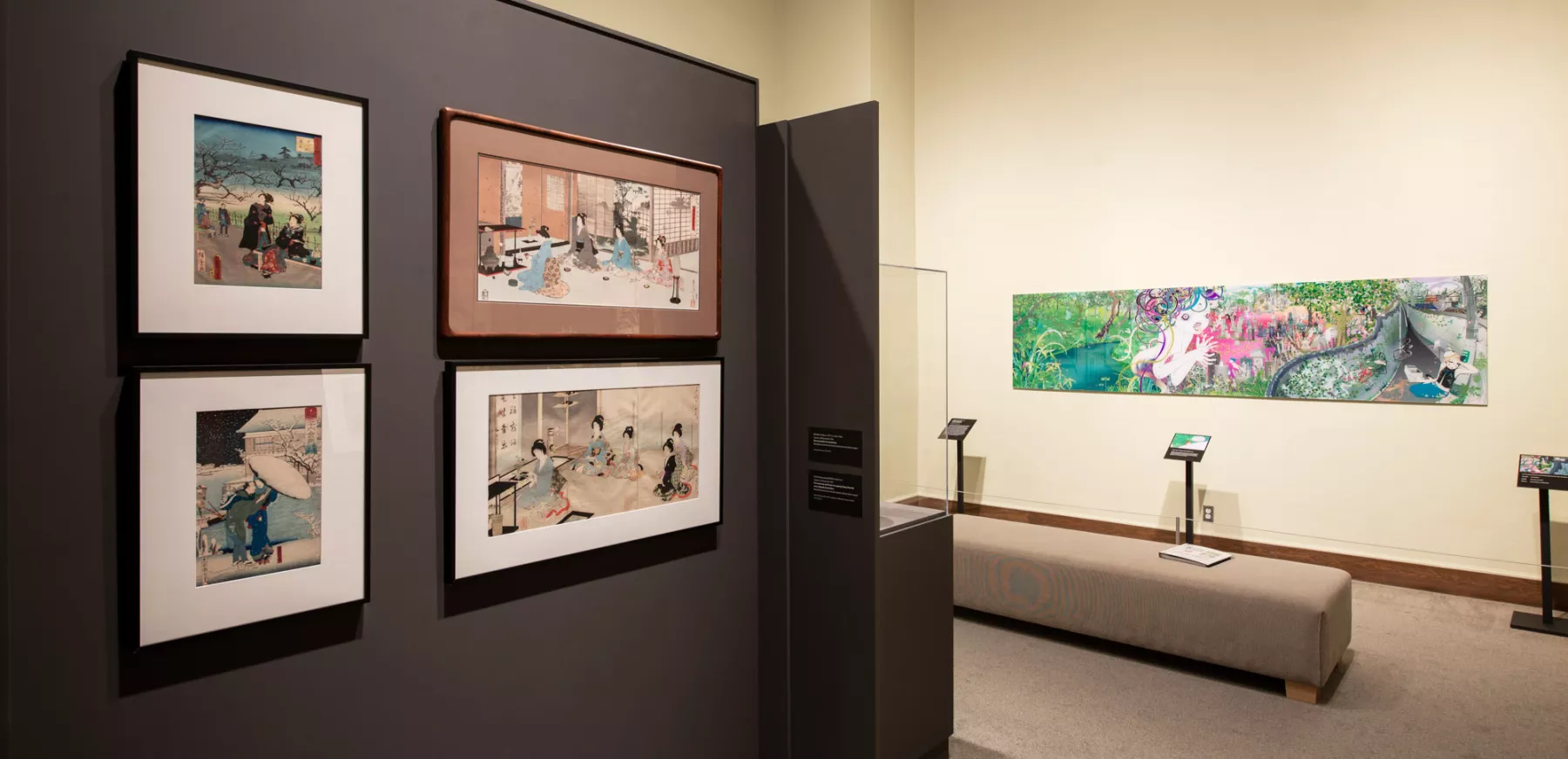 Gallery view of the Preble Murphy Gallery of Japanese Art with 4 framed prints on a wall to the left and a long colorful artwork on the yellow wall in the distance.