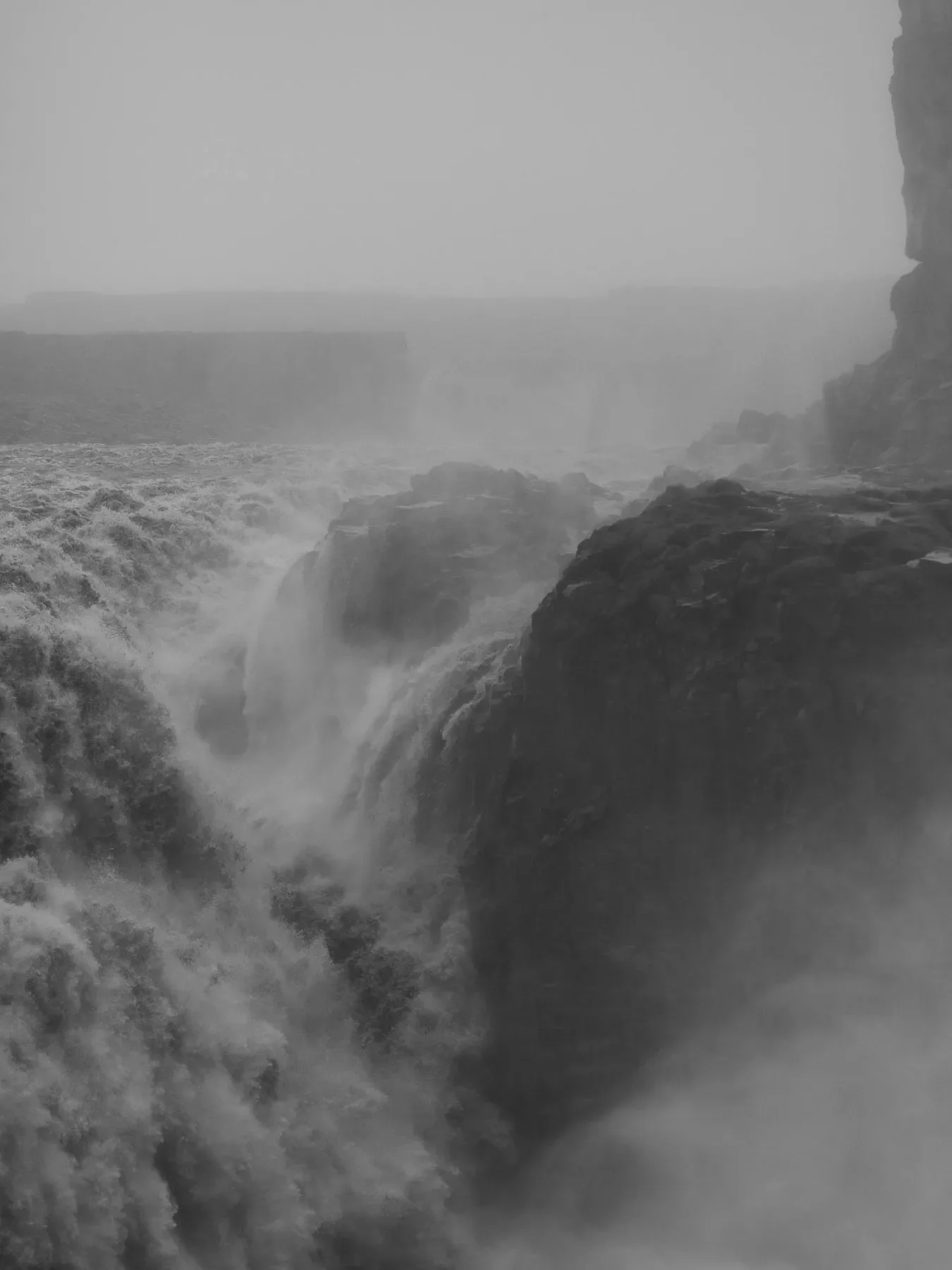 A dramatic black and white photograph of a powerful waterfall cascading over rocky cliffs, shrouded in mist and fog, creating a sense of movement and energy.