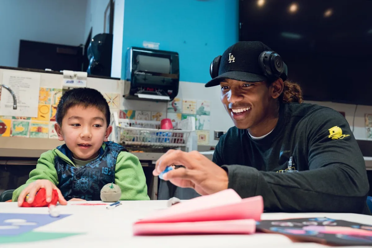 A young boy and a college athlete make art in an art studio.