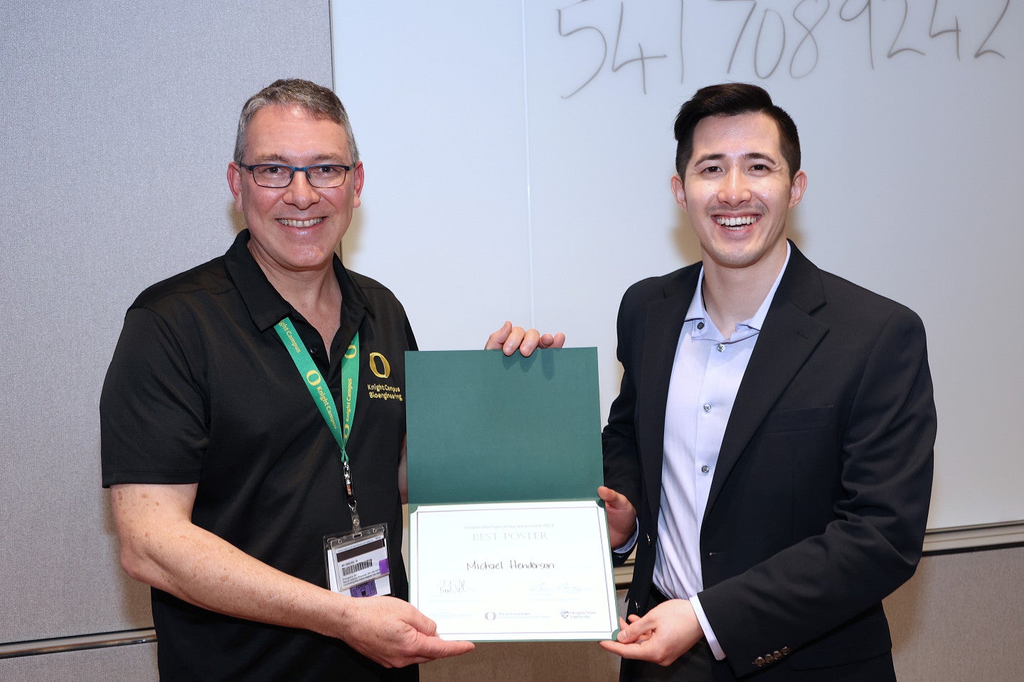 Man and man holding award certificate