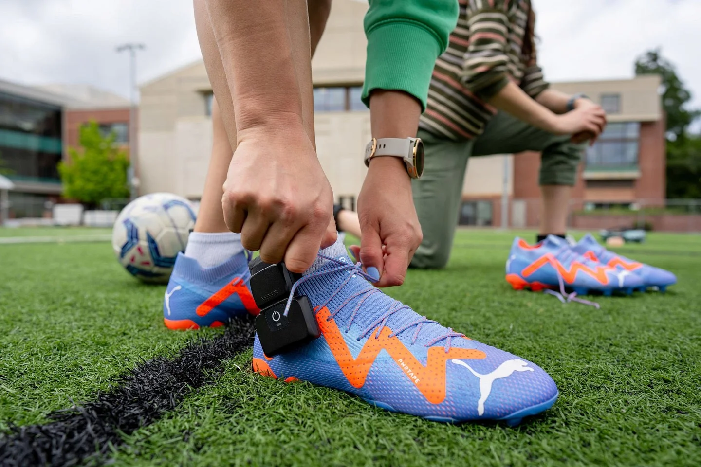 someone tying up a soccer cleat, attached with a sensor. 