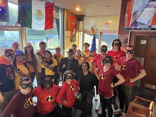 Group of people in halloween costumes, in a bar with flags