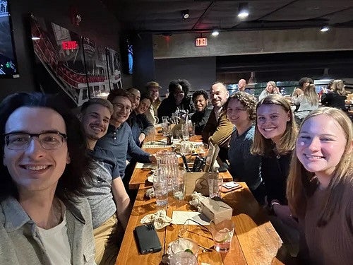 Group of people at a bar, at a conference, with dood and drinks on the table