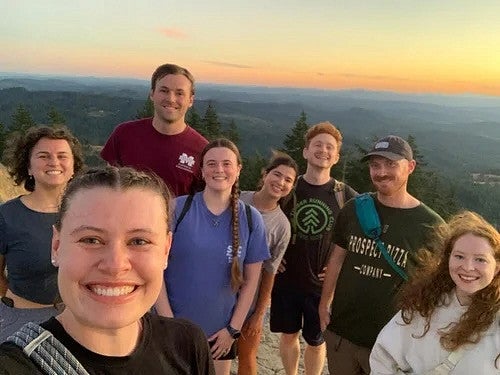 Group of people overlooking a sunset, after a hike