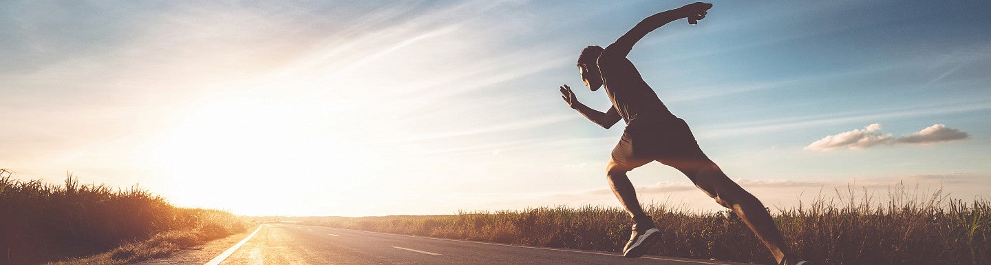 Runner taking off with outstretched leg in sunlight