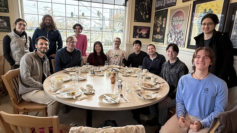 group of people around a round table, with lots of framed art behind them. 