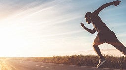 Runner taking off with outstretched leg in sunlight