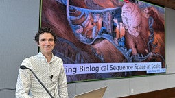 Man at lecture podium with animated slide behind him