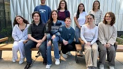 Group of students sitting and standing before shiny geometric backdrop