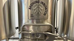 Image of tank with lettering reading "Brewing Innovation" and image of hop cone