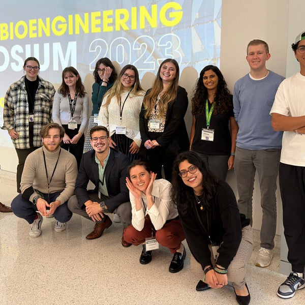 Group of attendees at the Oregon Bioengineering Symposium 2023 posing for a photo in front of a banner displaying the event's title.