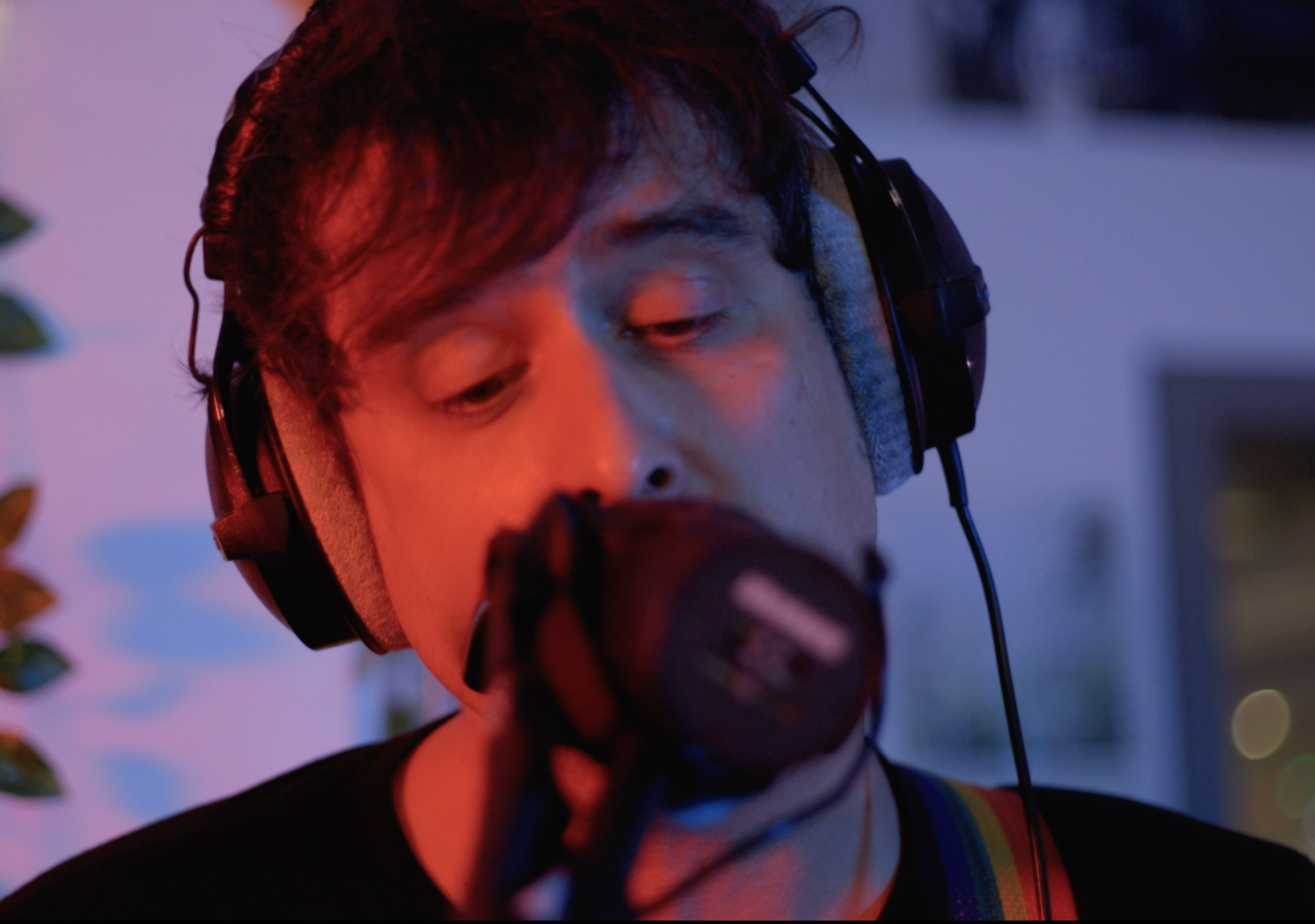 Middle-aged white man wearing headphone singing into microphone