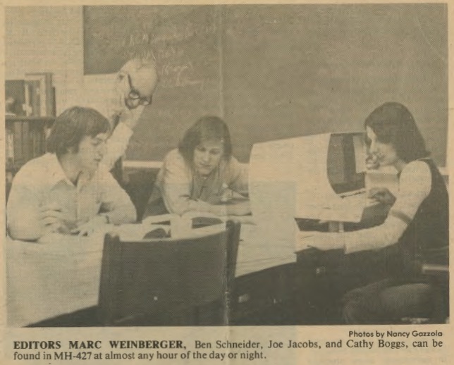 newspaper photograph of editors Marc Weinberger, Ben Schneider, Joe Jacobs, and Cathy Boggs gathered around a computer terminal