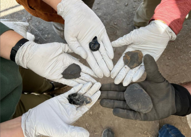 Five hands holding stone tools in a circle