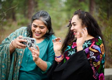 Two people are grinning and looking at a phone screen together. 