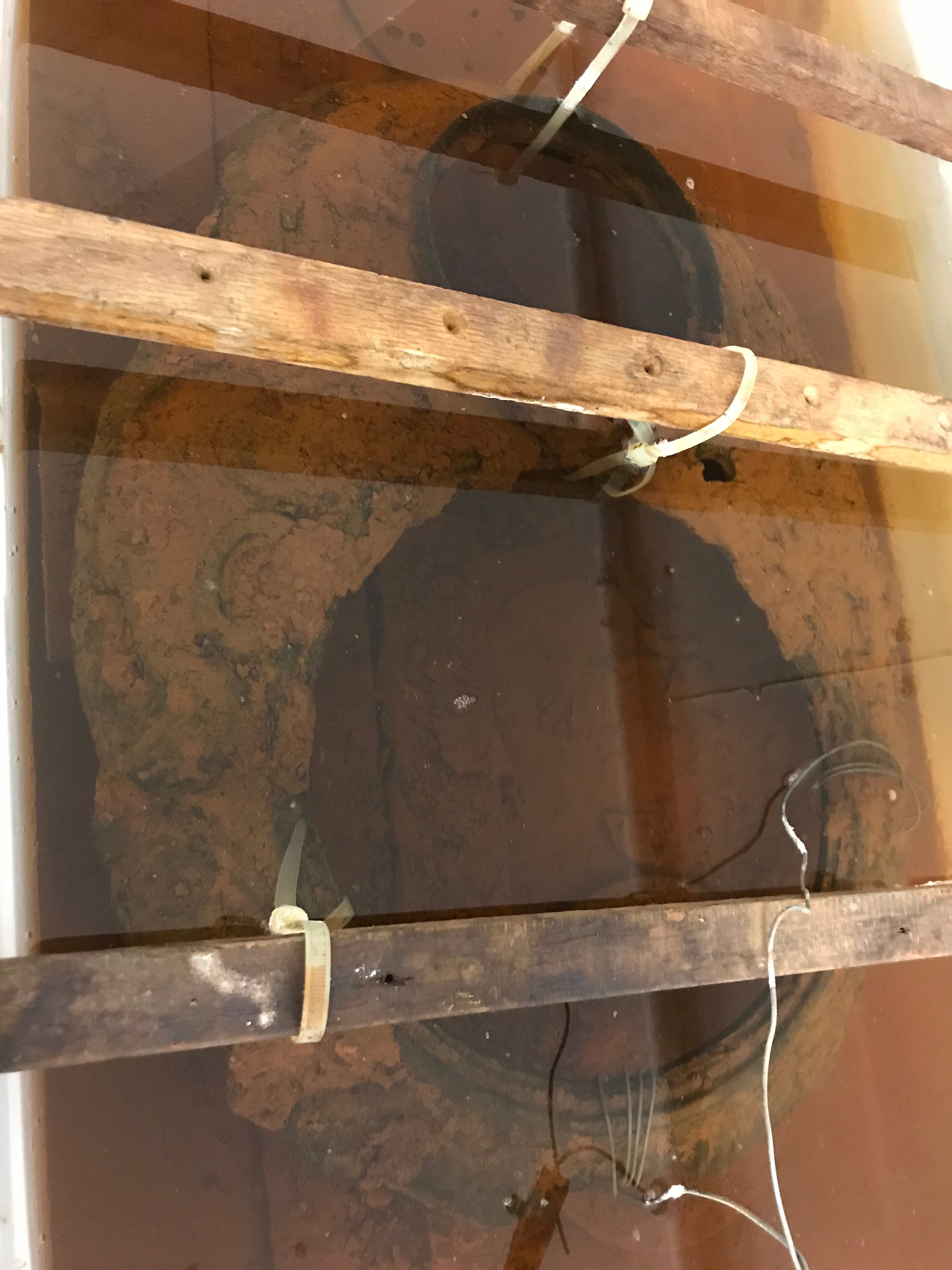 Rusty and dirty cast iron stovetop submerged in an electrolysis tank