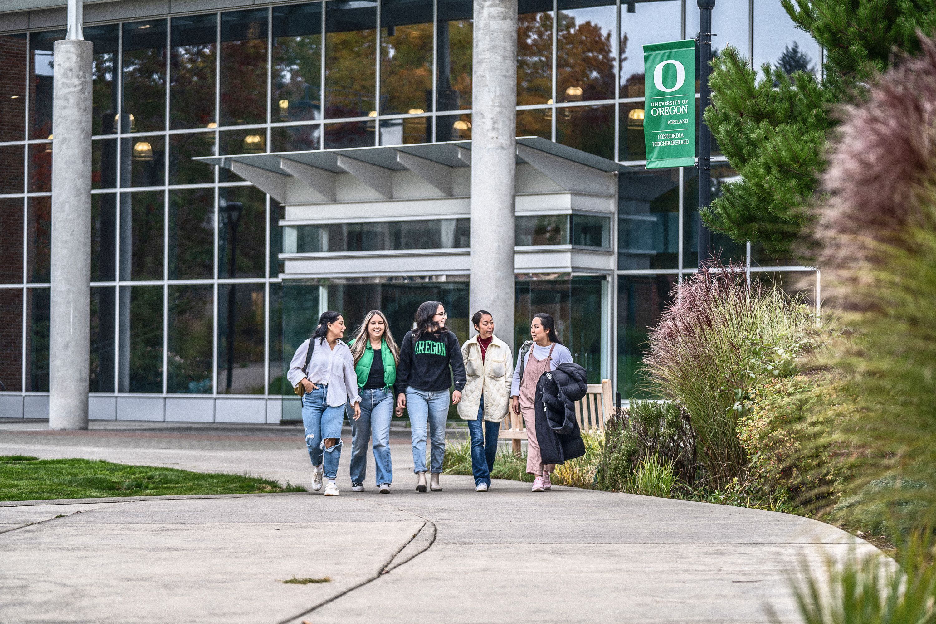 A photo of students outside walking away from the Library and Learning Center on the UO Portland campus