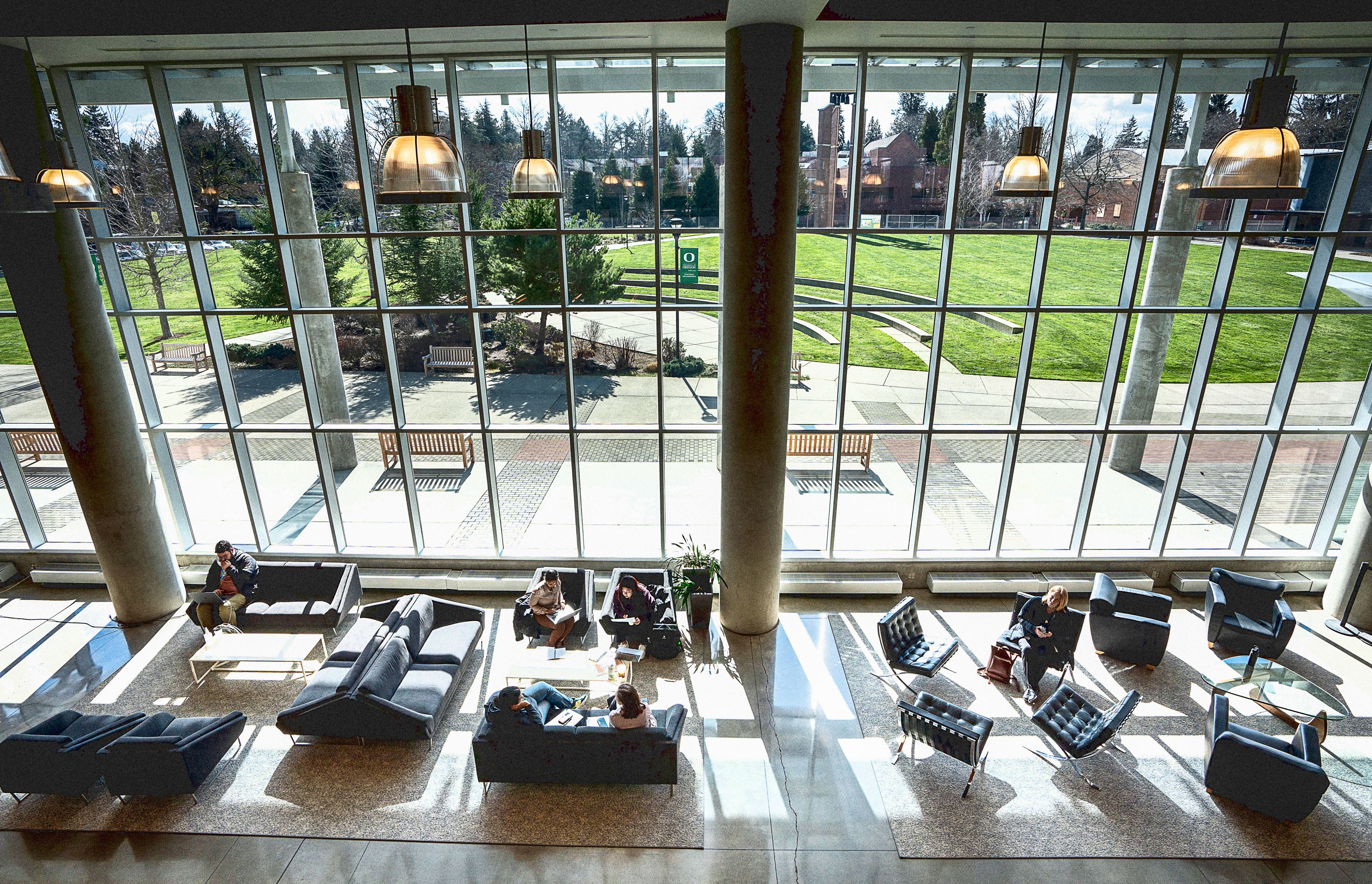 A photo of students sitting and talking inside the Library and Learning Center while looking out over a grassy area outside