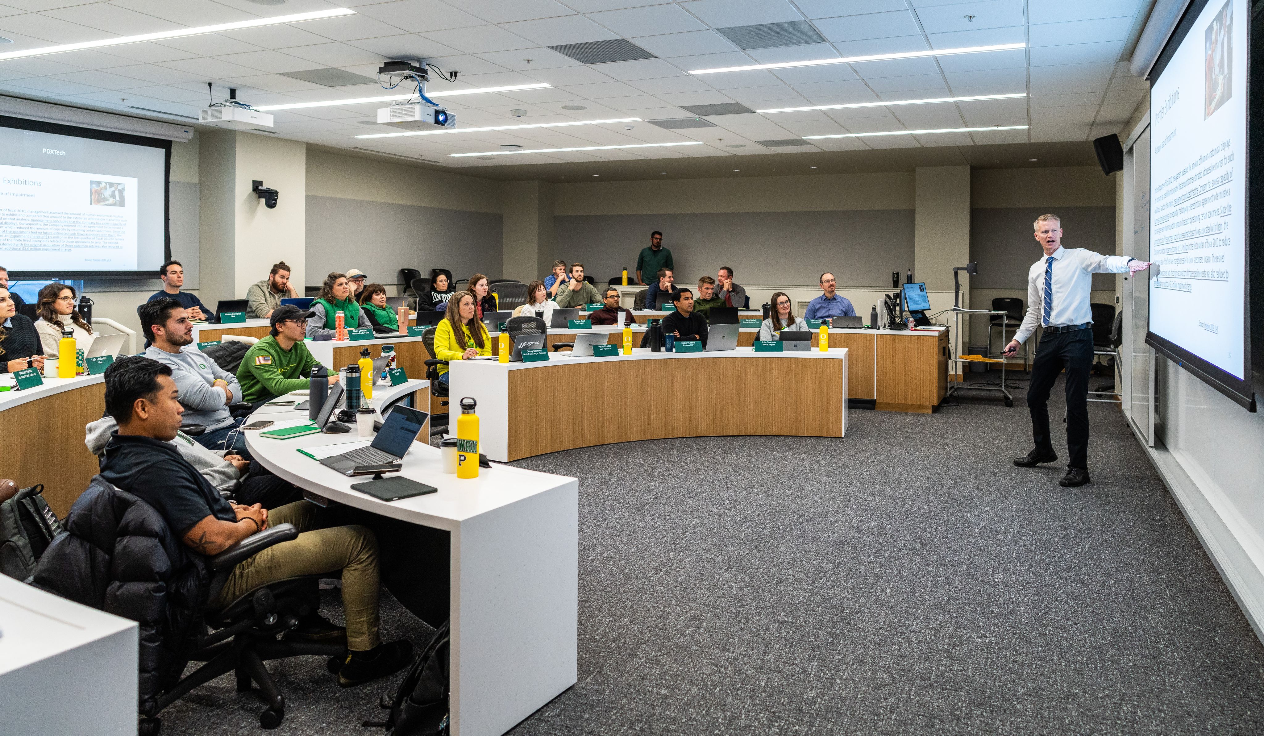 A photo of students listening to a professor lecture in a tiered classroom