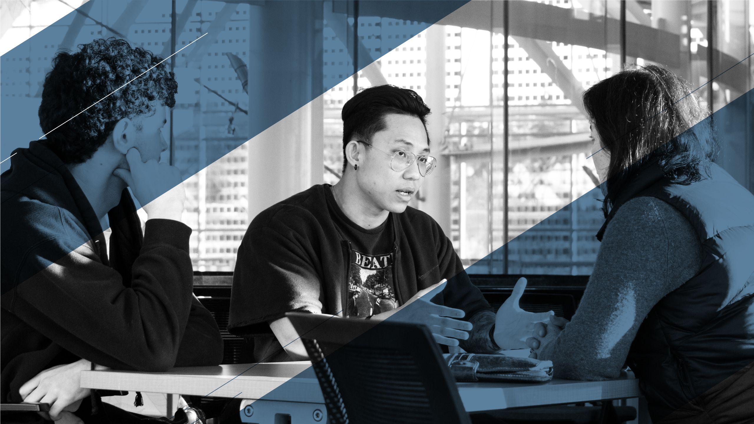 Three students sitting across from each other at a table, talking, with an added blue overlay.