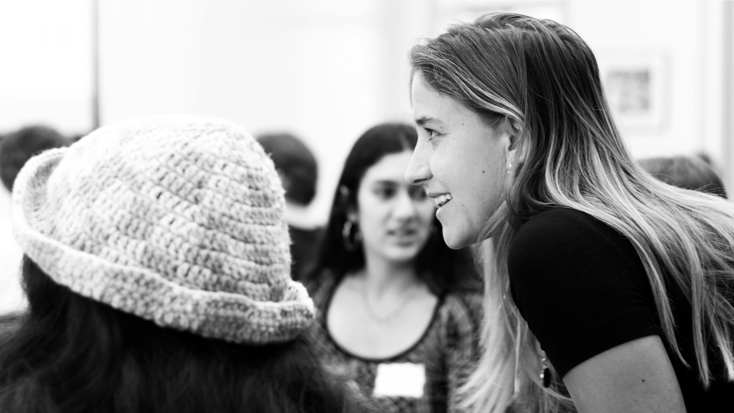 A close-up of one student leaning towards and talking to another student.