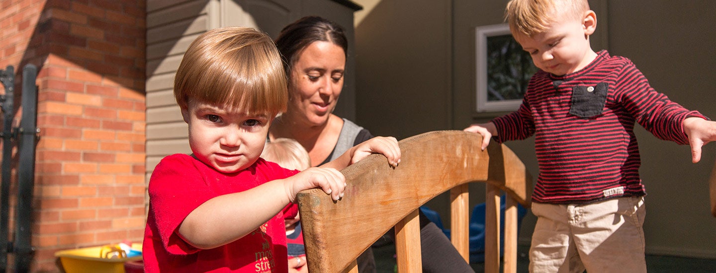 Supervised Toddlers walking on small bridge at Moss Street Children’s Center.
