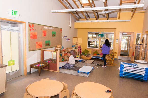 Classroom space offered for infants needing hands on supervision including soft play mats, and low seating at tables and other play spaces.