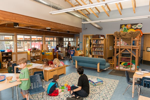 Classroom features soft mats, couches, work space, bookshelves, and reading areas.