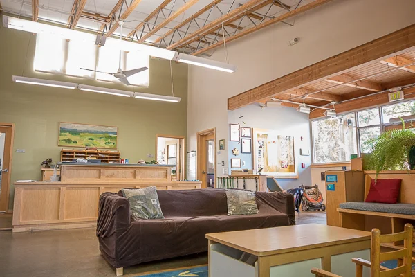 Lobby features brightly lit open space, couches, child size tables, and several windows.