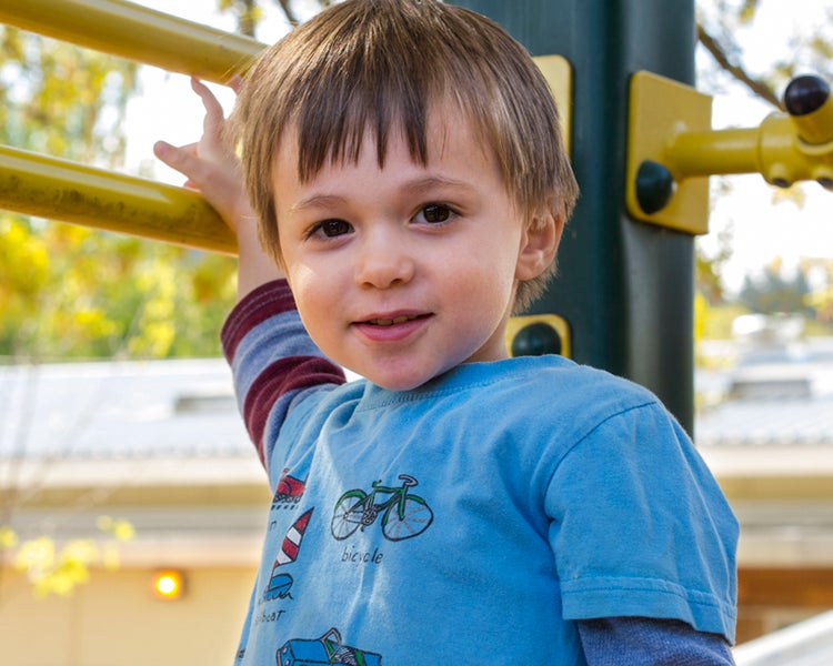 3 year old child sitting on play structure.