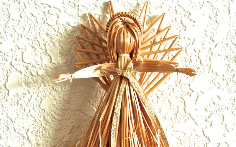 A wheat-woven angel against a white wall
