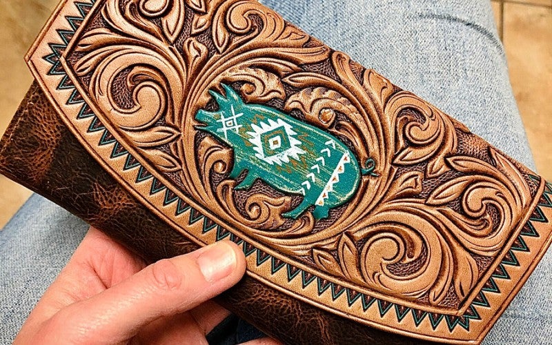 A brown leather wallet with a blue pig on the front flap.