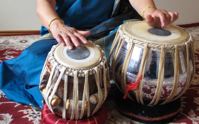 Nisha Joshi sits with two drums