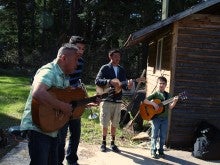 Four members of Mariachi los Temerosos stand outside in front of a house playing various instruments, including guitars and a trumpet.