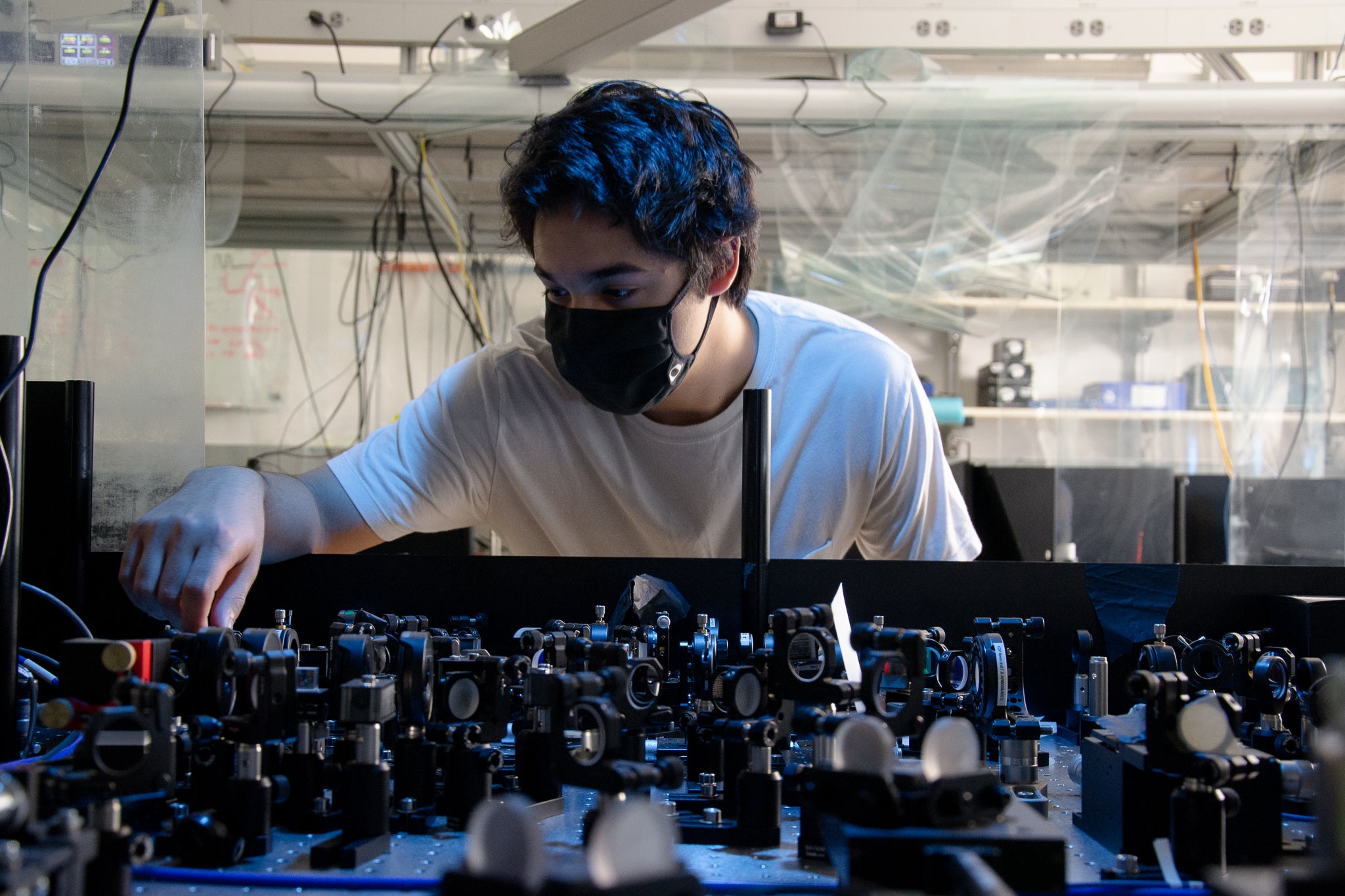 A person in a mask adjusts parts of a laser.