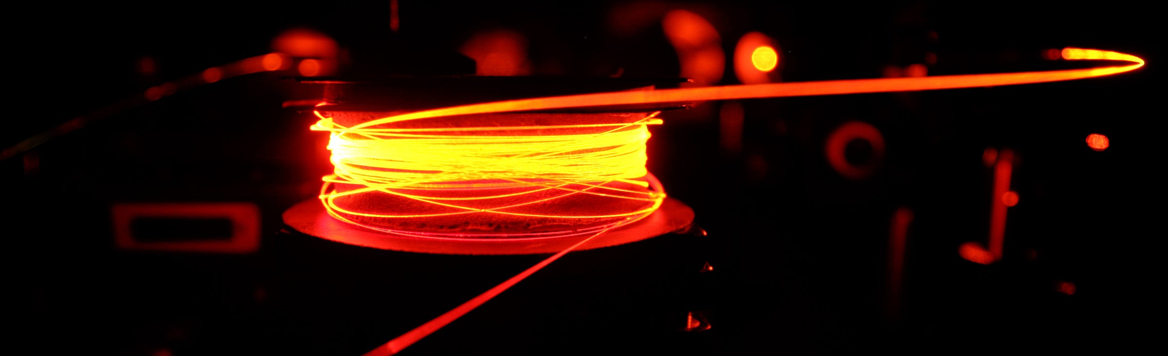 Light shines on a wire in a manner in which it appears to glow orange.