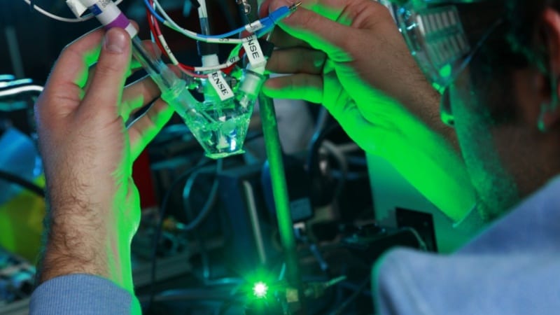 A person holds a piece of equipment in a lab.