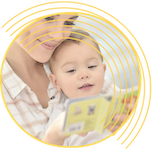 mother holding a toddler looking at a children's book