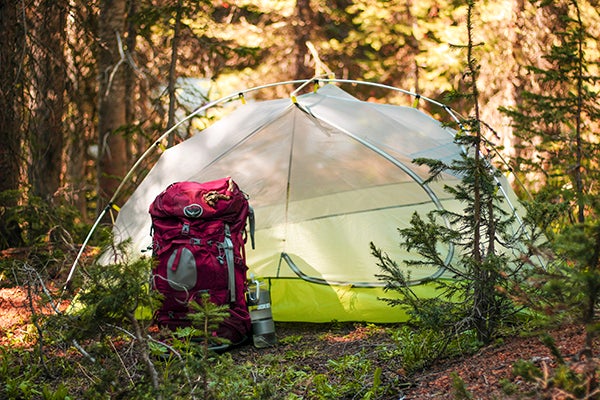 Camping tent and hiking backpack at camp site.