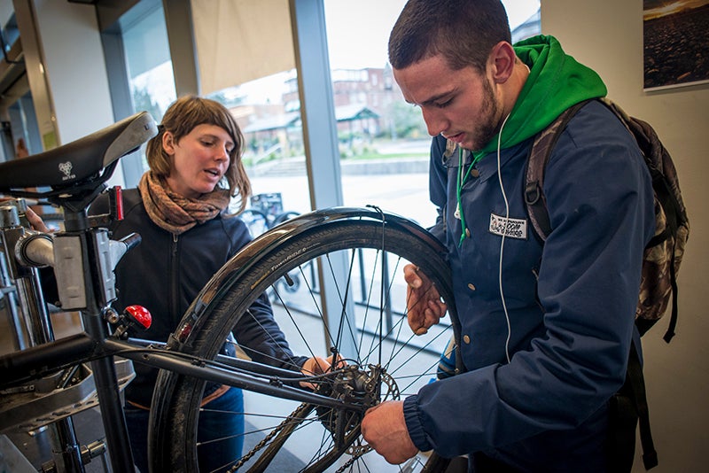 Students repairing bicycle wheel and gears.