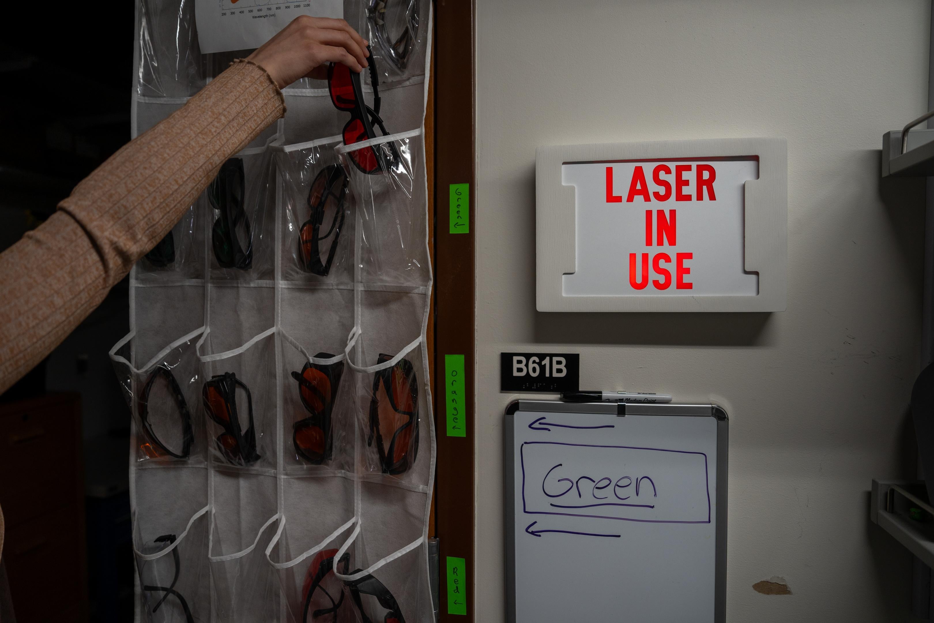 A neon sign displays the words laser in use. 