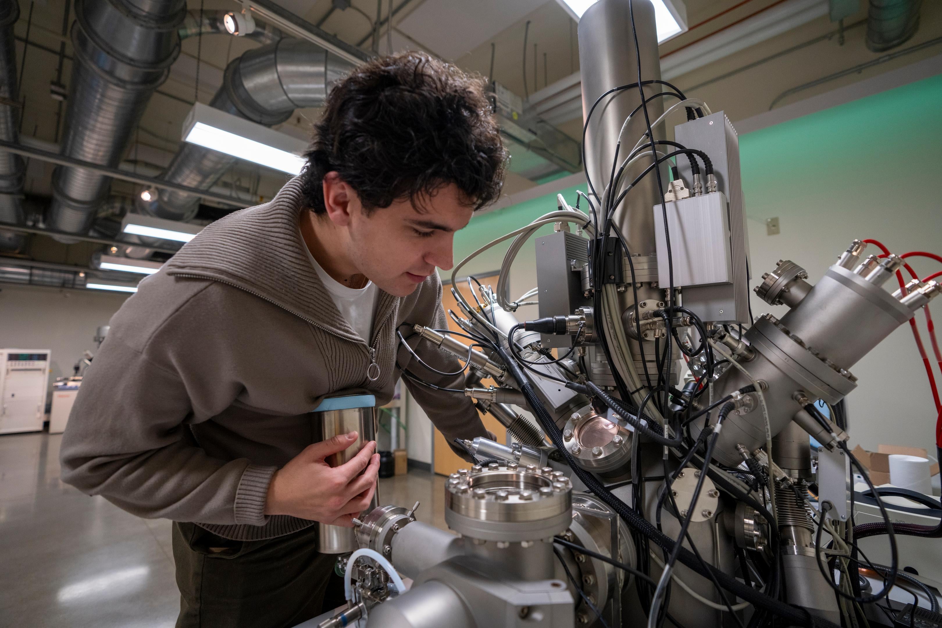A student leans over a large microscope.