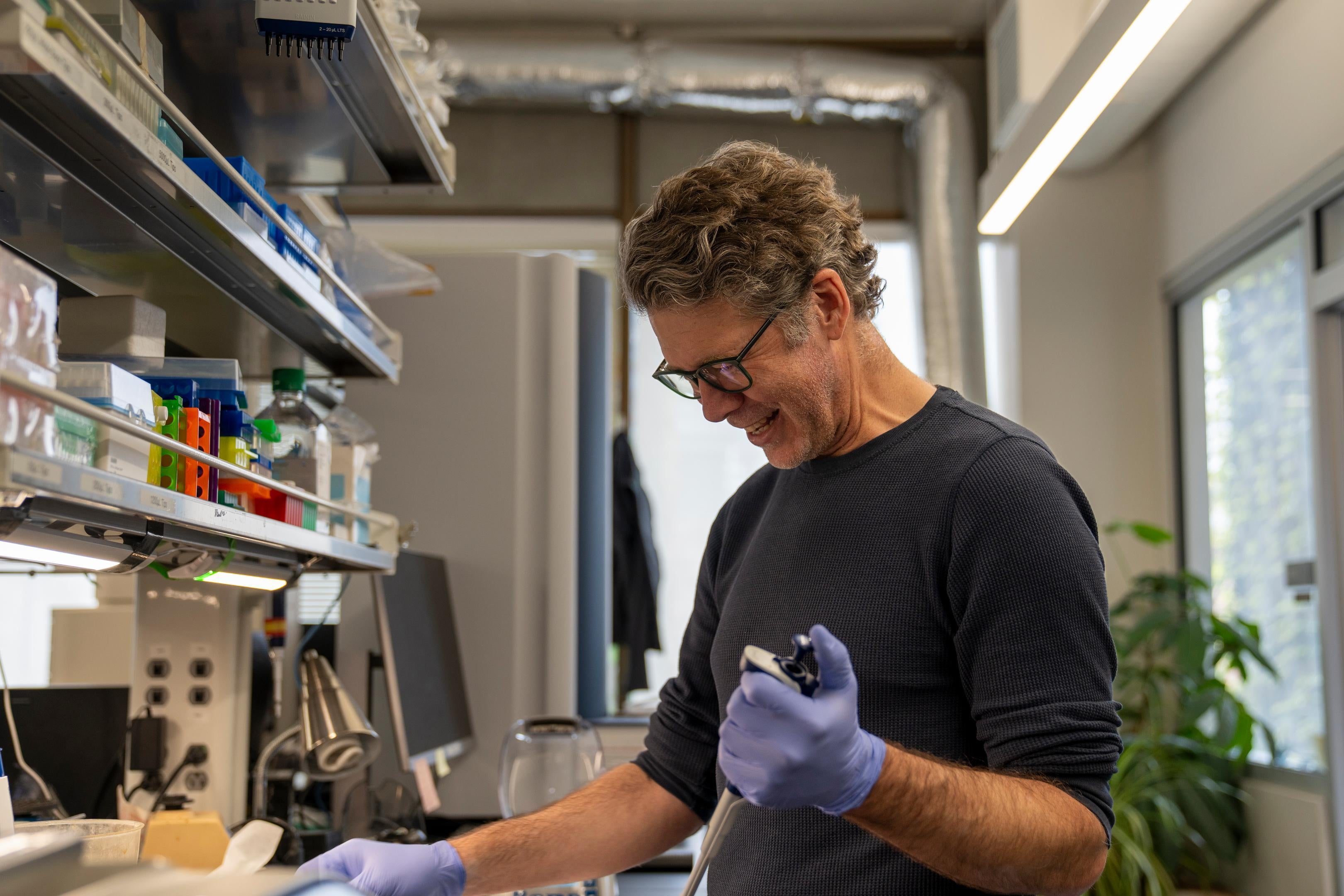 A staff member holds a pipette to prepare samples in a lab.
