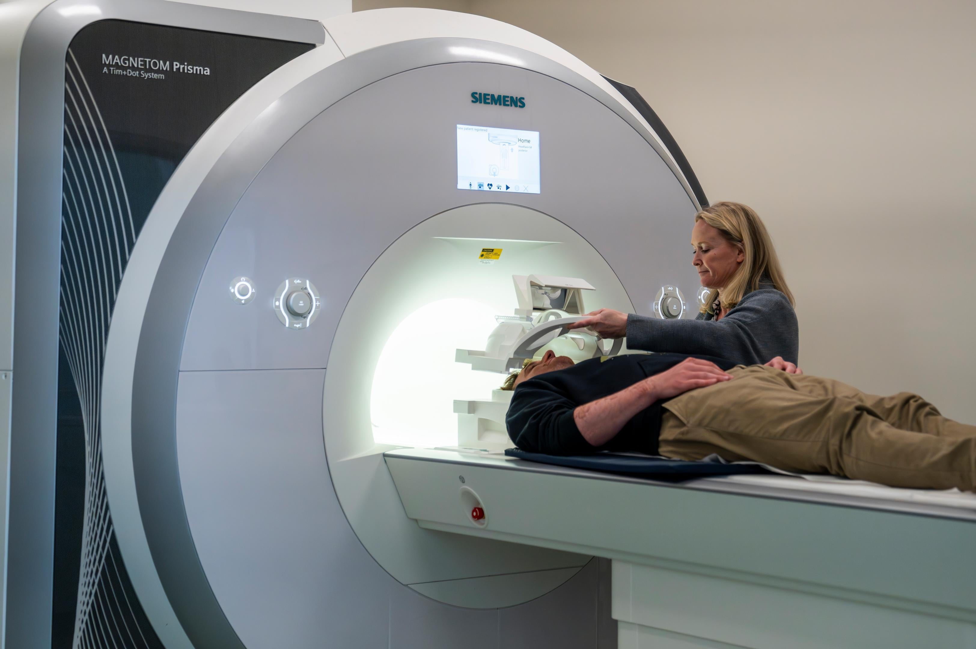 A researcher positions a person laying on the patient table of an MRI machine. 