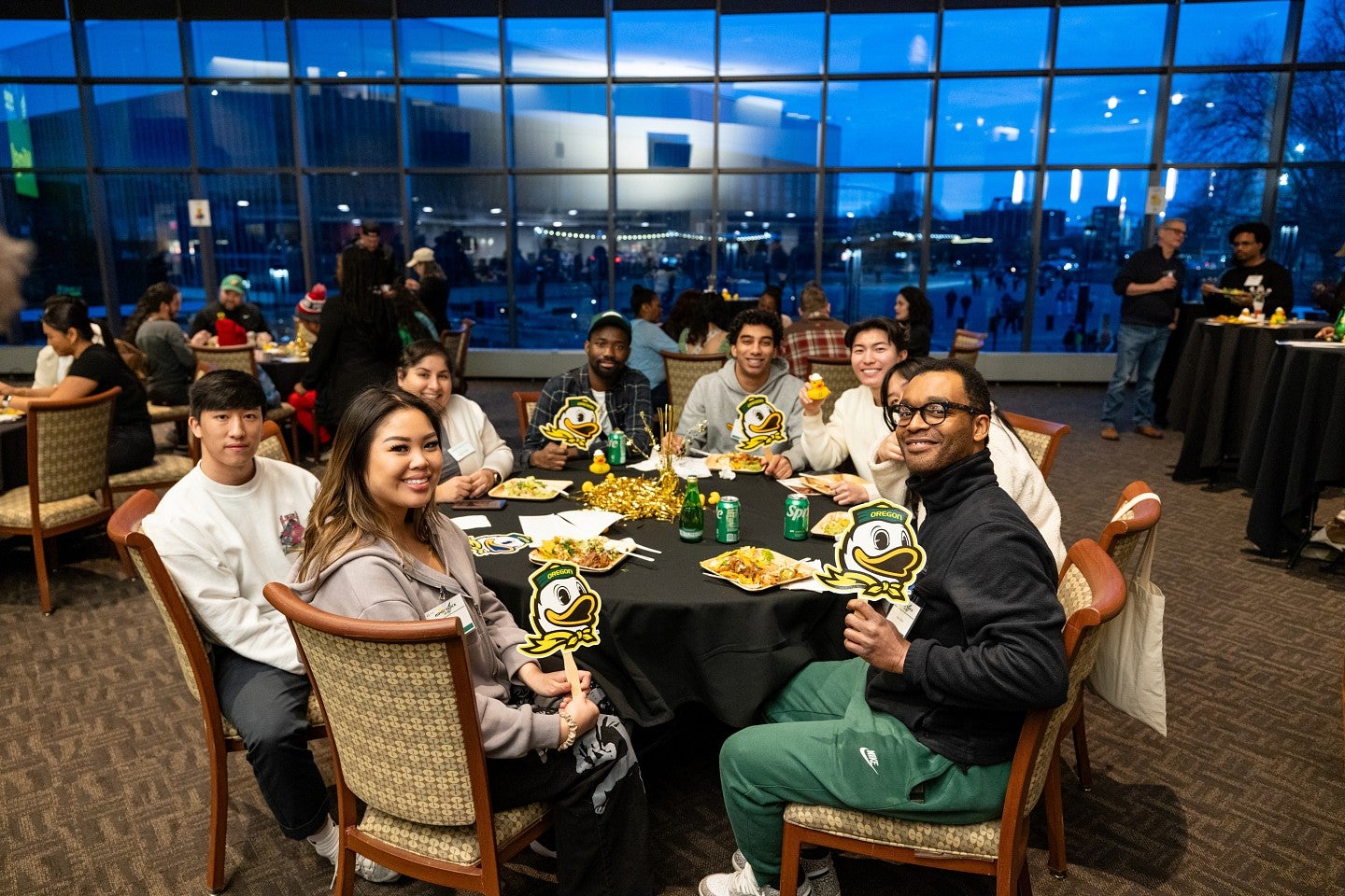 Students sit around a table holding Duck signs and smiling