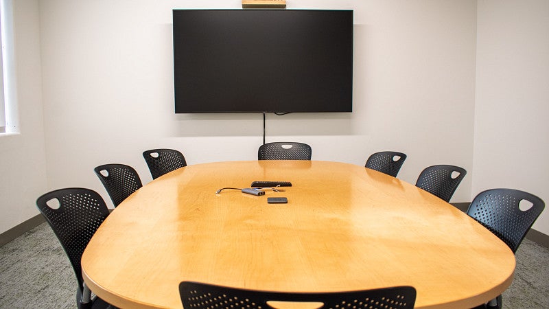 Small conference table with seating for eight and a screen on the wall